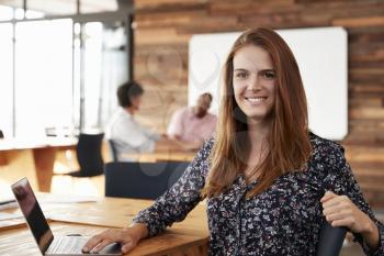 Young white woman with long red hair sitting in office