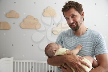Father Comforting Newborn Baby Son In Nursery