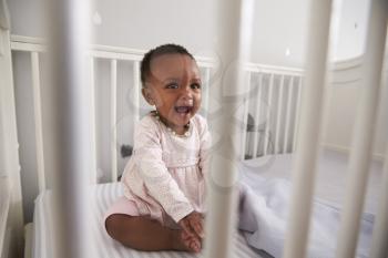 Happy Baby Girl Playing In Nursery Cot