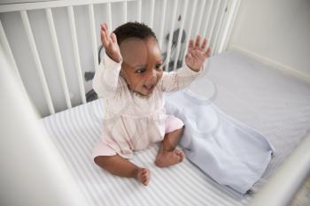 Happy Baby Girl Playing In Nursery Cot