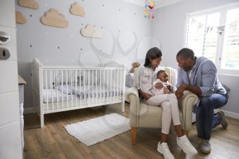 Parents Sitting In Nursery With Baby Daughter