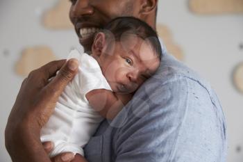 Close Up Of Father Holding Newborn Baby Son In Nursery