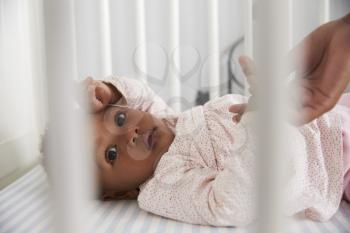 Close Up Of Baby Girl Lying In Nursery Cot