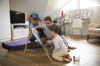 Father And Children Drawing On Chalkboard In Playroom