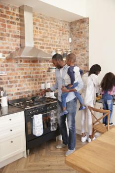 Children Helping Parents To Prepare Meal In Kitchen