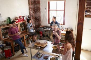 Five friends stand hanging out in kitchen, elevated view