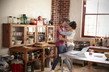 Young mixed race couple dancing in kitchen, full length