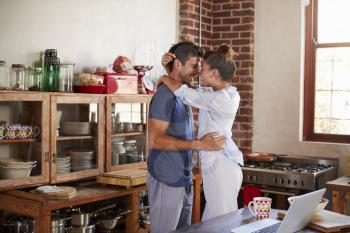 Happy Hispanic couple embracing in kitchen in the morning