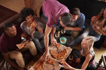 Young adults eating pizzas at a party at home, elevated view