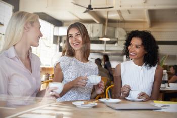Three Businesswomen Meet In Coffee Shop Shot Through Window