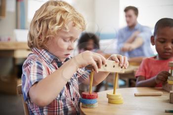 Montessori Pupil Working At Desk With Wooden Shapes