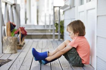 Female Pupil At Montessori School Putting On Wellington Boots
