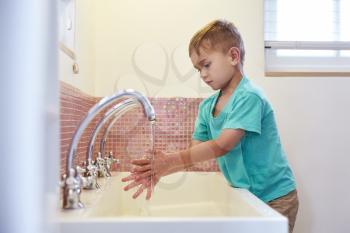 Male Pupil At Montessori School Washing Hands In Washroom