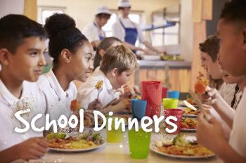 Primary school children eat school dinners in cafeteria