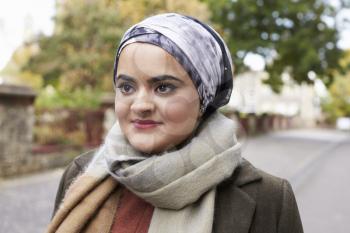 British Muslim Woman Walking On Street In Urban Environment
