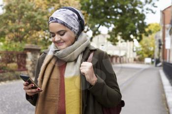 British Muslim Woman Using Mobile Phone In Urban Setting