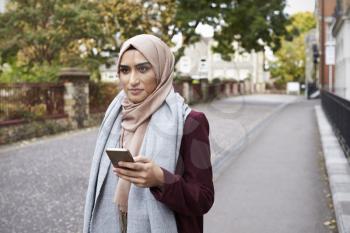 British Muslim Woman Using Mobile Phone In Urban Setting