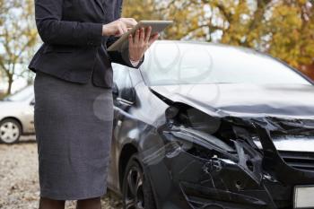 Loss Adjuster With Digital Tablet Inspecting Damaged Car