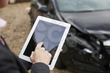 Loss Adjuster With Digital Tablet Inspecting Damaged Car