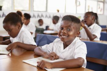 Elementary school boy smiling at camera at his desk in class