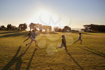 Four elementary school children running in an open field
