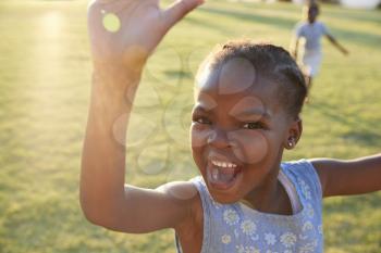 African elementary school girl waving to camera outdoors