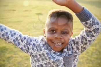 African elementary school boy waving to camera outdoors