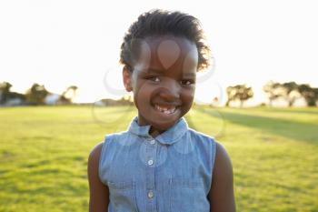 African elementary school girl smiling in a park, close up