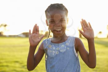 Portrait of African elementary school girl with hands raised