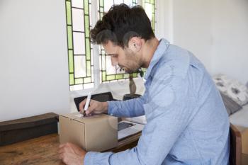 Man In Bedroom Running Business From Home Labeling Goods