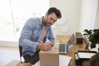 Man In Bedroom Running Business From Home Labeling Goods