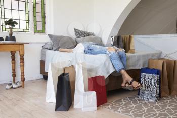 Woman Back From Shopping Trip Surrounded By Bags Lies On Bed