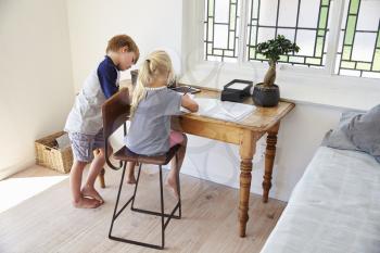 Boy And Girl In Bedroom With Digital Tablet Doing Homework