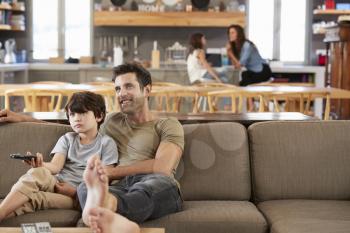 Father And Son Sitting On Sofa In Lounge Watching Television