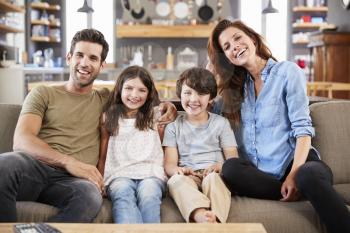 Portrait Of Happy Family Sitting On Sofa In Open Plan Lounge