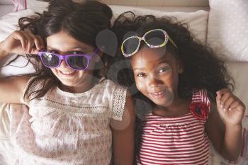 Portrait Of Two Girls Wearing Sunglasses In Bedroom Together
