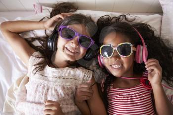 Portrait Of Two Girls Wearing Sunglasses And Listening To Music