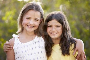 Portrait of two happy young girls embracing outdoors