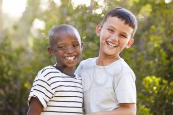 Portrait of two boys outdoors laughing and looking to camera