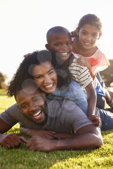 Happy black family lying in a pile on grass outdoors