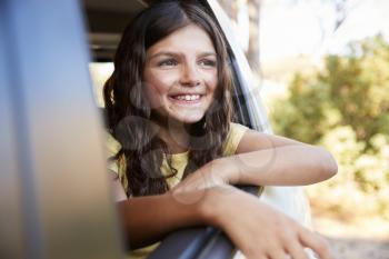 Young girl smiling and looking out of open car window