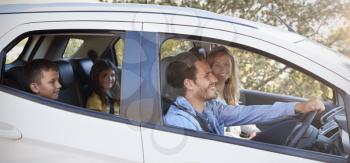 Happy young family with two children driving in their car
