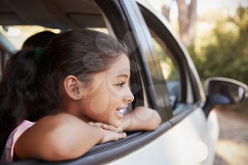Young black girl looking out of car window smiling, side view