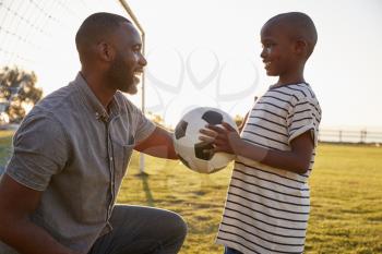 A boy holds a football while playing with his dad