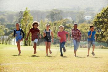Six pre-teen friends running in a park, front view