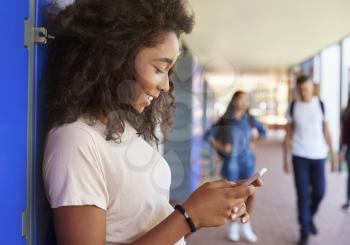 Black teenage girl using smartphone at break time in school