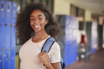 Happy black teenage girl smiling in high school corridor