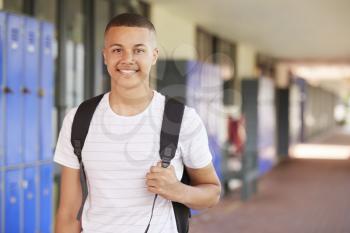 Happy mixed race teenage boy smiling in high school corridor