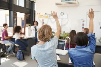 Pupils raising hands in a high school science lesson