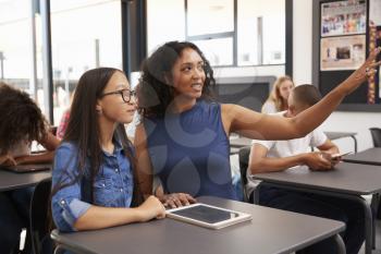 Teacher working with teenage schoolgirl points to the board